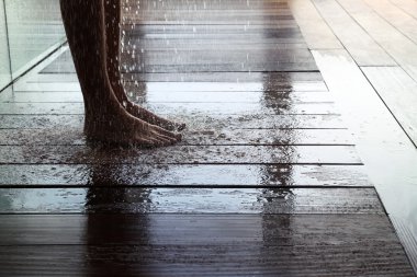 Islak ahşap zemin alarak duş üzerinde duran adam