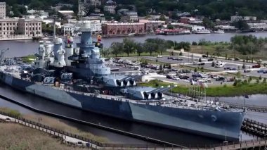 Low aerial view of the USS North Carolina BB-55 With Multiple Gun Turrets Docked at Wilmington Harbor, Military Vessel on Display