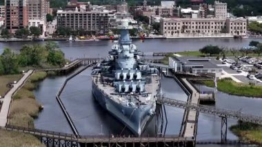 Low aerial view of the USS North Carolina BB-55 With Multiple Gun Turrets Docked at Wilmington Harbor, Military Vessel on Display