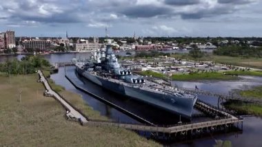 Low aerial view of the USS North Carolina BB-55 With Multiple Gun Turrets Docked at Wilmington Harbor, Military Vessel on Display