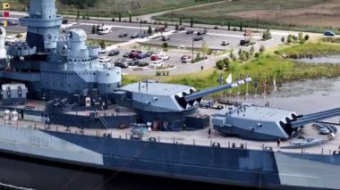 Low aerial view of the USS North Carolina BB-55 With Multiple Gun Turrets Docked at Wilmington Harbor, Military Vessel on Display