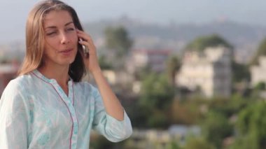 Telefonu konuşurken, gülümseyerek, hayattan zevk Smartphone kullanarak mutlu güzel kadın. Çatı Big City açık havada onun göğsüne için değerdir. Katmandu, Nepal