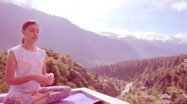 Güzel genç kadın yapıyor Yoga meditasyon Lotus açık havada oturma Asana Mat çatı ev yüksek dağlar, tonlama, lavanta güneş. Güneş ışınları, sabah, yaz, Manali, Hindistan, Himalayalar