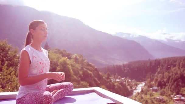 Vackra unga kvinnan gör Yoga Meditation Lotus utomhus sittande Asana matta tak hus höga bergen, Sun. Toning, lavendel. Solen strålar, morgon, sommar, Manali, Indien, Himalaya — Stockvideo