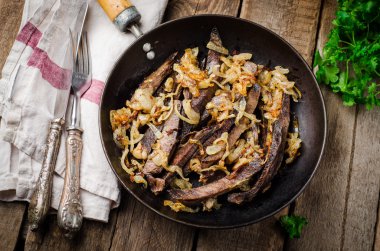 Ahşap arka planda vintage demir tencerede kavrulmuş sığır kalbi. Seçici odaklama