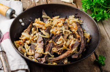 Ahşap arka planda vintage demir tencerede kavrulmuş sığır kalbi. Seçici odaklama