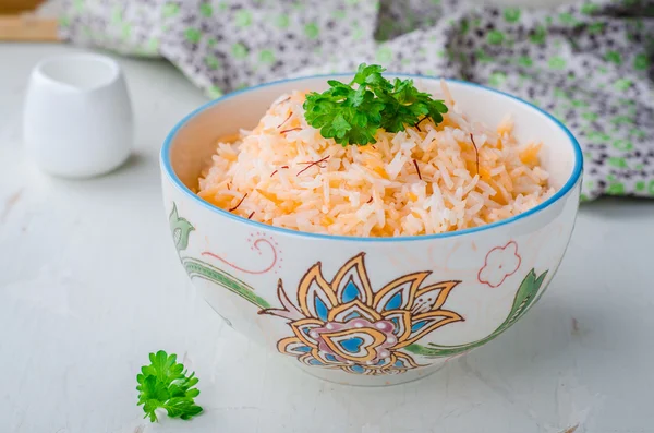 Rice pilaf with saffron in ornament bowl on wooden background. Selective focus — 스톡 사진