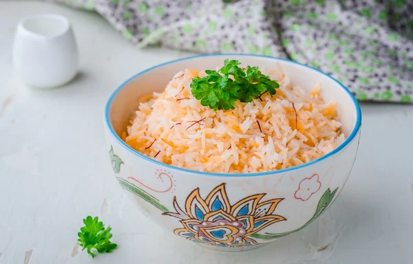 Rice pilaf with saffron in ornament bowl on wooden background. Selective focus — 스톡 사진