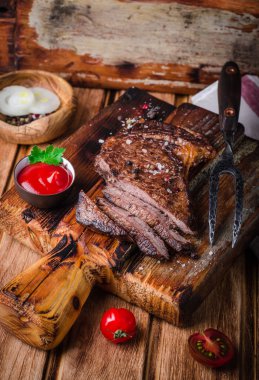 Ahşap arka plan üzerinde kesme tahtası üzerinde baharat ve ketçap ile Dilimlenmiş orta nadir ızgara Beef biftek