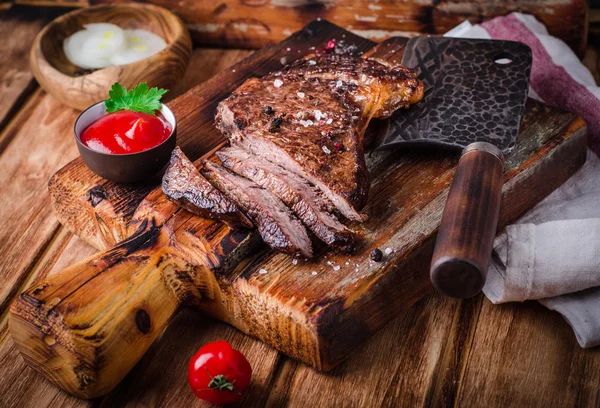 Bife grelhado médio em fatias com especiarias e ketchup na tábua de corte em fundo de madeira — Fotografia de Stock