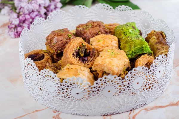 Smíšené baklava v bílé desky na mramorové pozadí. Ramadánových jídel, turecké arabskou kuchyní. Selektivní fokus — Stock fotografie