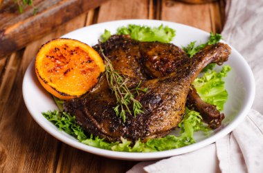 Kekik ahşap arka plan üzerinde beyaz plaka ile Confit ördek bacaklar. Seçici odak