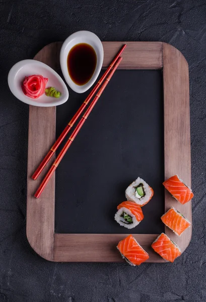 Rollos de sushi con salmón y pepino sobre fondo de pizarra de pizarra vintage. Enfoque selectivo —  Fotos de Stock