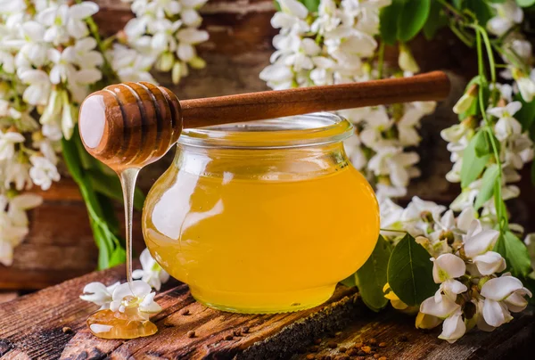 Miele di acacia in gar su fondo legno. L'umore primaverile. Concentrazione selettiva. Immagine tonica — Foto Stock