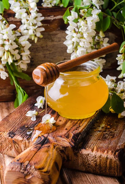 Miele di acacia in gar su fondo legno. L'umore primaverile. Concentrazione selettiva. Immagine tonica — Foto Stock