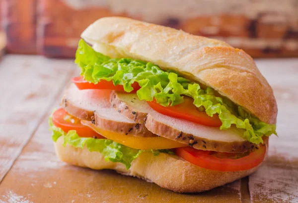 Sandwich with roasted chicken, leaves salad and tomatoes on wooden baskgraund. Selective focus — 스톡 사진