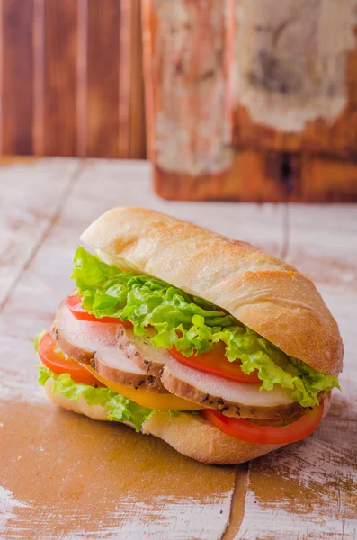 Sandwich with roasted chicken, leaves salad and tomatoes on wooden baskgraund. Selective focus — 스톡 사진