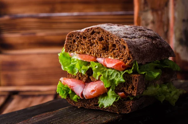 Homemade Sandwich with salmon and lemon on dark wooden background. Selective focus. Picnic concept — Stock Photo, Image