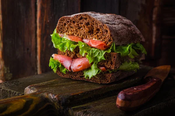 Homemade Sandwich with salmon and lemon on dark wooden background. Selective focus. Picnic concept — Stock Photo, Image