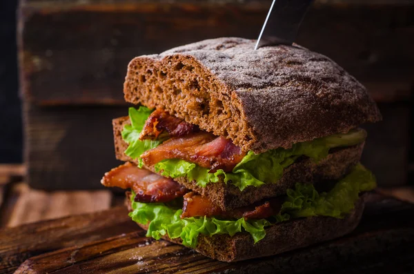 Sandwich burger à la laitue, bacon rôti sur planche à découper en bois foncé. Concentration sélective — Photo