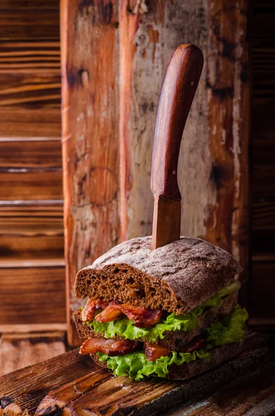 Sandwich burger à la laitue, bacon rôti sur planche à découper en bois foncé. Concentration sélective — Photo