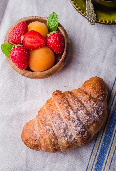 Croissant with strawberry and apricots on over white linen tablecloth.. Breakfast concept. Selective focus. Top view — Stock Photo, Image