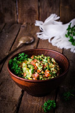 Taze tabbouleh, bir Orta Doğu salatası, ahşap arka plan üzerinde kil kase. Seçici odak. Tonlu görüntü