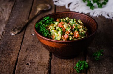 Taze tabbouleh, bir Orta Doğu salatası, ahşap arka plan üzerinde kil kase. Seçici odak. Tonlu görüntü