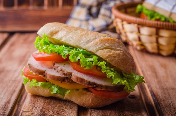 Sandwich maison avec tomates fraîches et poitrine de poulet dans le panier sur fond en bois. Concentration sélective. Concept pique-nique — Photo