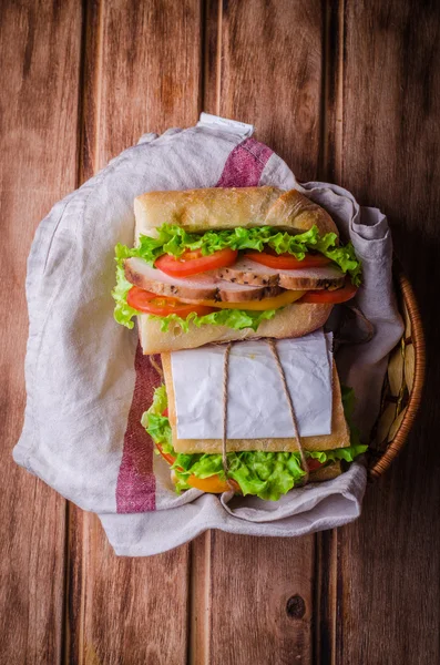 Hausgemachtes Sandwich mit frischen Tomaten und Hühnerbrust im Korb auf Holzboden. Selektiver Fokus. Ansicht von oben. Picknick-Konzept — Stockfoto