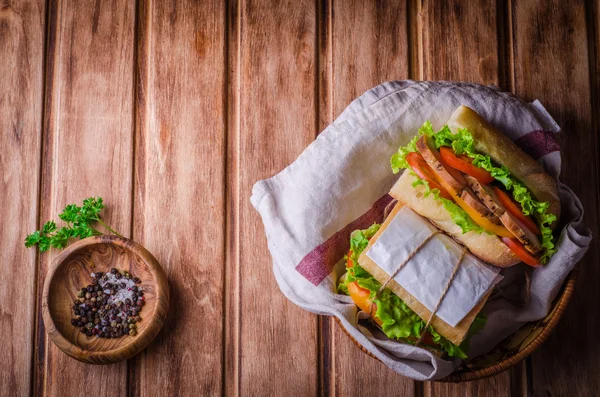 自制三明治，在木质背景的篮子里放新鲜的西红柿和鸡胸肉。选择性聚焦。顶部视图。与一些文本的地方。野餐概念 — 图库照片