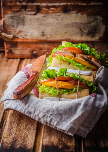 Σπιτικό σάντουιτς με φρέσκες ντομάτες και στήθος κοτόπουλου στο καλάθι σε ξύλινο φόντο. Επιλεκτική εστίαση. Αίσθηση πικ-νικ — Φωτογραφία Αρχείου