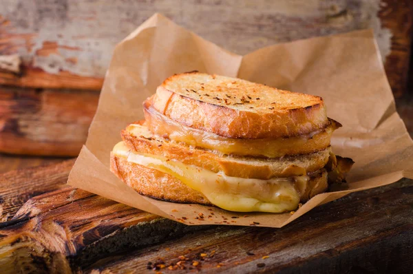 Сэндвич с сыром на гриле с перцем чили на бумаге на деревянной доске. Селективный фокус . — стоковое фото