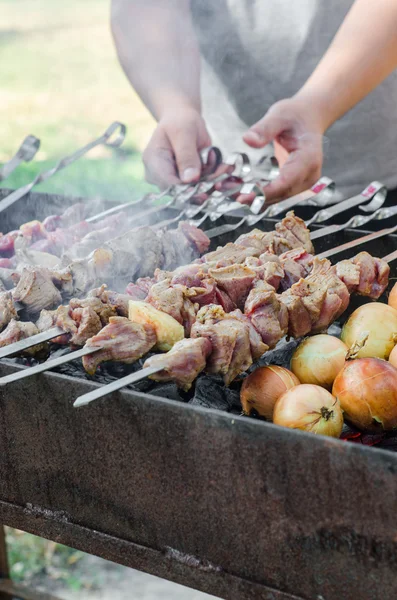 Man cooking marinated shashlik or shish kebab, chiken meat grilling on metal skewer, close up. Selective focus — Stock Photo, Image
