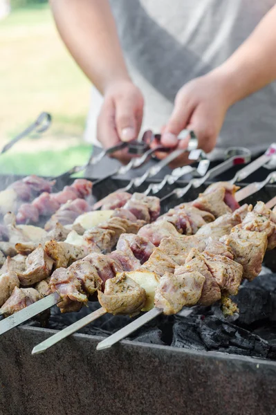 Homem cozinhando shashlik marinado ou shish kebab, carne de chiken grelhando em espeto de metal, de perto. Foco seletivo — Fotografia de Stock