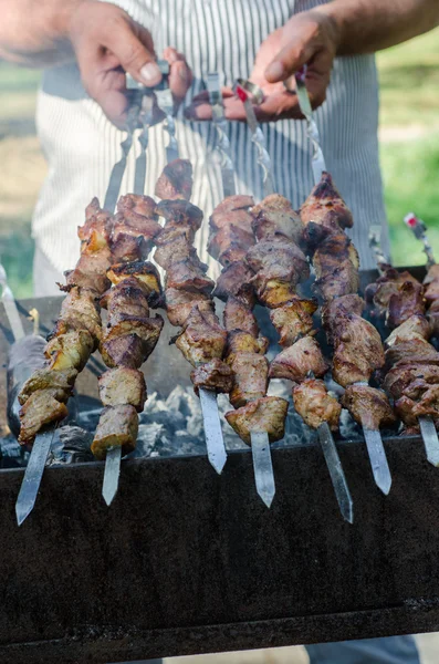 Homem cozinhando shashlik marinado ou shish kebab, carne de chiken grelhando em espeto de metal, de perto. Foco seletivo — Fotografia de Stock