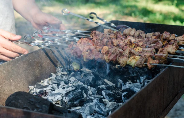 Homem cozinhando shashlik marinado ou shish kebab, carne de chiken grelhando em espeto de metal, de perto. Foco seletivo — Fotografia de Stock