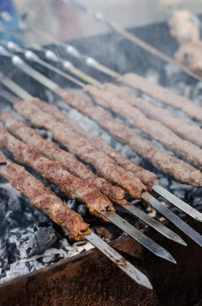 Homem cozinhando shashlik marinado ou shish kebab, carne de chiken grelhando em espeto de metal, de perto. Foco seletivo — Fotografia de Stock