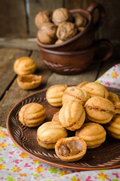 Печенье в форме грецких орехов с сгущенным молоком - притуплено в глиняной чаше на деревянном деревенском фоне. Селективный фокус — стоковое фото