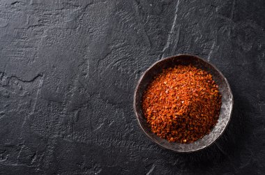 Karanlık taş zemin üzerine metal plaka üzerindeki kırmızı biber biber ezilmiş. Seçici odak. Üstten Görünüm