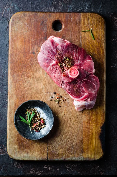 Carne crua de carneiro com especiarias na tábua de corte e fundo escuro. Foco seletivo — Fotografia de Stock