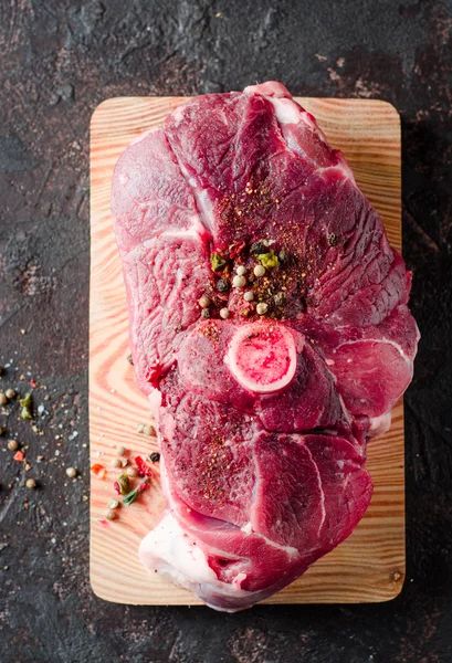 Carne de cordero cruda con especias sobre tabla de cortar y fondo oscuro. Enfoque selectivo. Vista superior —  Fotos de Stock