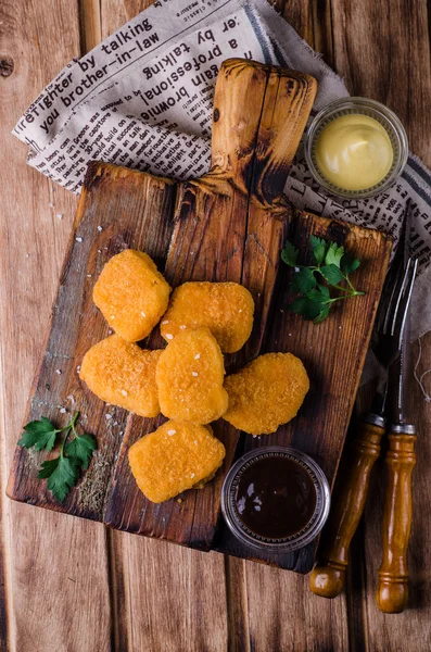 Chicken Nuggets on wooden cutting board with ketchup and sauce, on wooden background. Selective focus. Top view — Stock Photo, Image