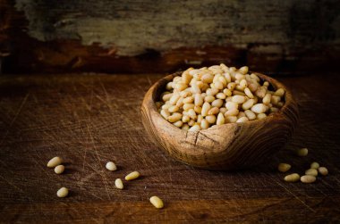 Ahşap arka planda tahta kasede çam fıstığı. Tonlanmış resim, Seçici odak