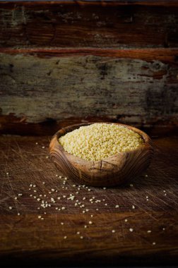 Tahta kasedeki çiğ organik kuskus. Koyu ahşap sırt kaplama. Seçici odaklanma. Tonu ayarlanmış resim