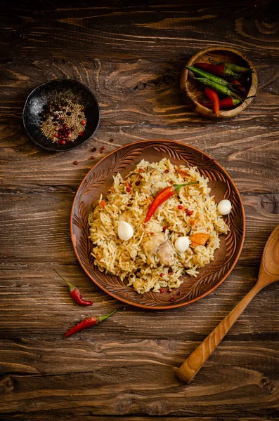 Csirke Biryani. Rizspilaf csirkével, fokhagymával és chili paprikával, agyagtányéron, fa háton. Ramadán kaja. Indiai konyha. Szelektív fókusz. Tonozott kép — Stock Fotó