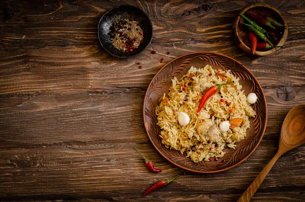 Pollo Biryani. Pilaf de arroz con pollo, ajo y chile en plato de barro sobre fondo de madera. Comida Ramadán. Cocina india. Enfoque selectivo. Imagen tonificada —  Fotos de Stock