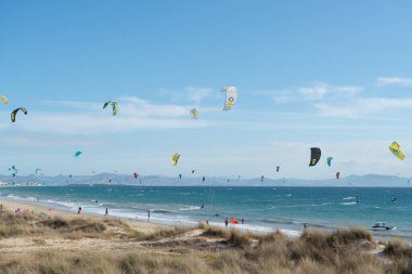 Birçok uçurtma sörfçüsü uçurtma paraşütleriyle Tarifa sahilinde havalanır.