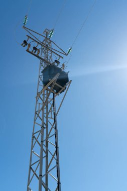 Mavi gökyüzü önünde elektrik iletimi ve dağıtımı için elektrik direği