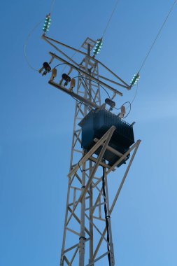 Mavi gökyüzü önünde elektrik iletimi ve dağıtımı için elektrik direği